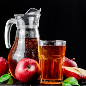 Apple juice in a jug and a glass on the table.