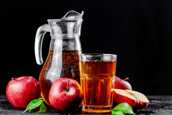 Apple juice in a jug and a glass on the table.