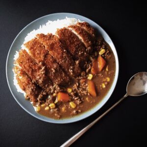 Chicken katsu curry over rice on black background