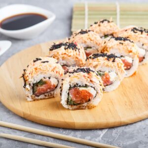 Japanese maki sushi rolls with salmon, sesame, chopsticks, soy sauce and marinated ginger