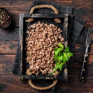 Pan Fried ground beef and lamb meat in a wooden tray with herbs. Wooden background. Top view