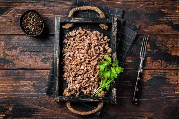 Pan Fried ground beef and lamb meat in a wooden tray with herbs. Wooden background. Top view